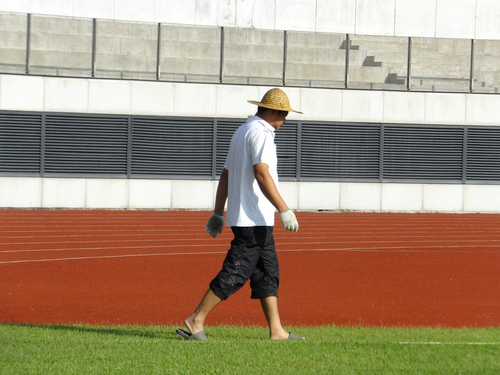 实拍深圳宝安体育馆足球场景观，有工人在维护有市民在跑步