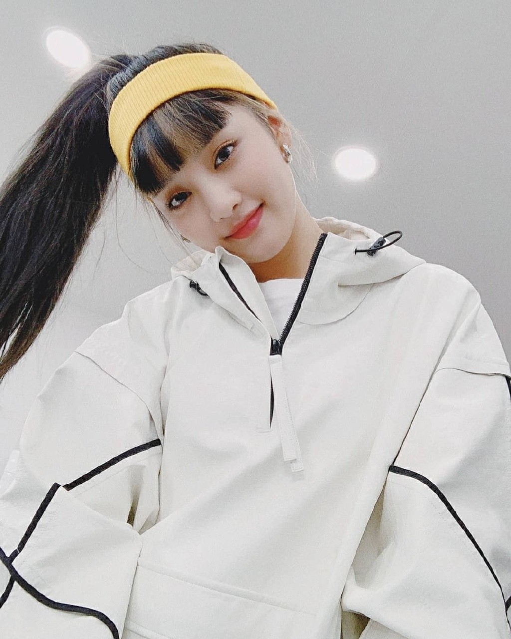 她是组合梦幻主唱，穿白底黑线休闲套装，发带增加运动感